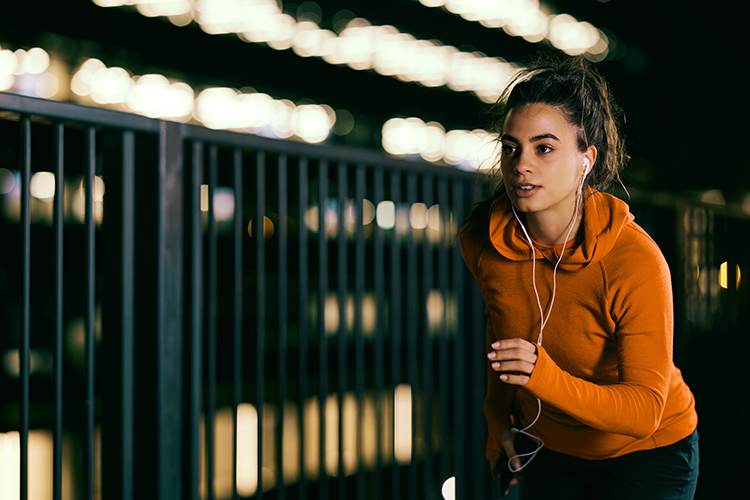 Young, fit, beautiful woman running through a railway station at night