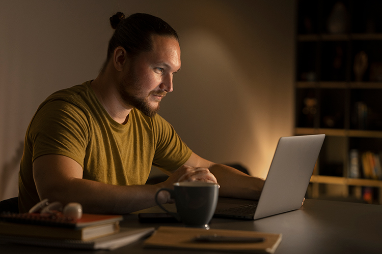 Mann arbeitet abends am Laptop