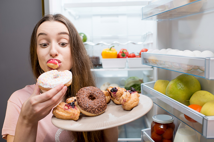 Young woman eating sweets straight from the fridge