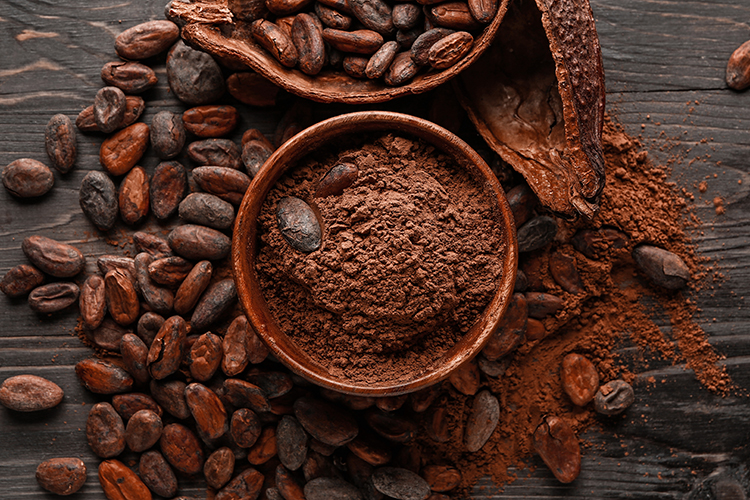 Bowl with cocoa powder and cocoa beans on a wooden background