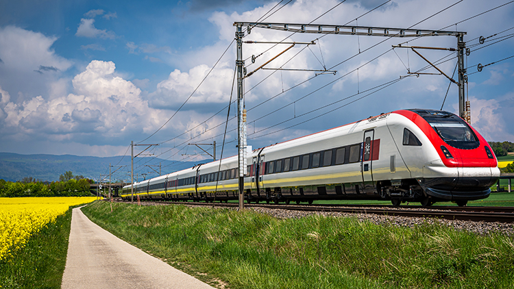 Tåg från SBB (CFF, FFS) som kör genom ett rapsfält på våren i Chavornay (kantonen Vaud), Schweiz