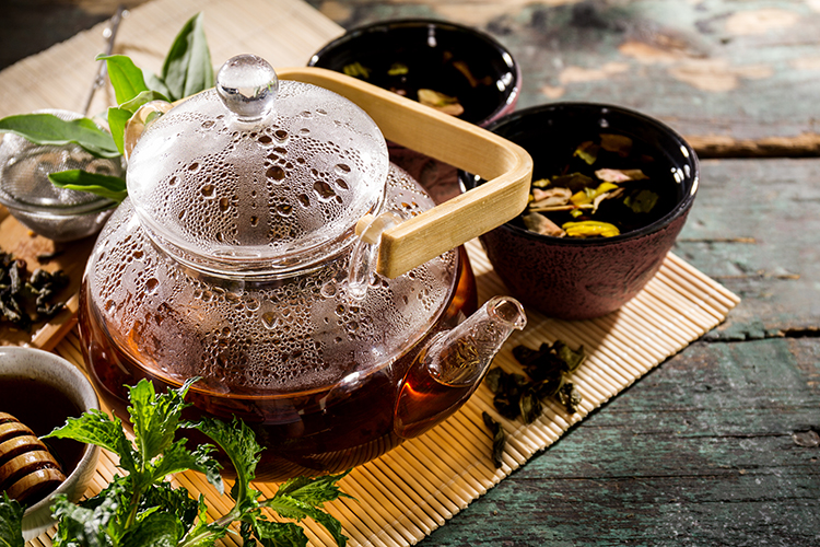 Tasty Fresh Green Tea in a Glass Teapot on a Rustic Wooden Table