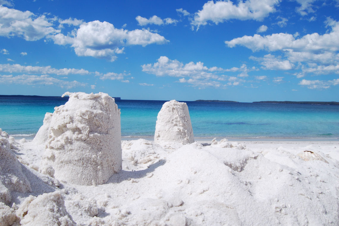 Hyams Beach, junto con la popular playa australiana de Whitehaven, es conocida por sus arenas cristalinas de cuarzo blanco y aguas turquesas. Esta arena tiene un 98 % de sílice pura y, a diferencia de la arena normal, no retiene el calor, lo que la hace cómoda para caminar descalzo en un día caluroso.