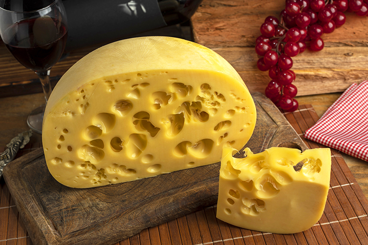 Meule de fromage suisse avec de gros trous sur une planche en bois