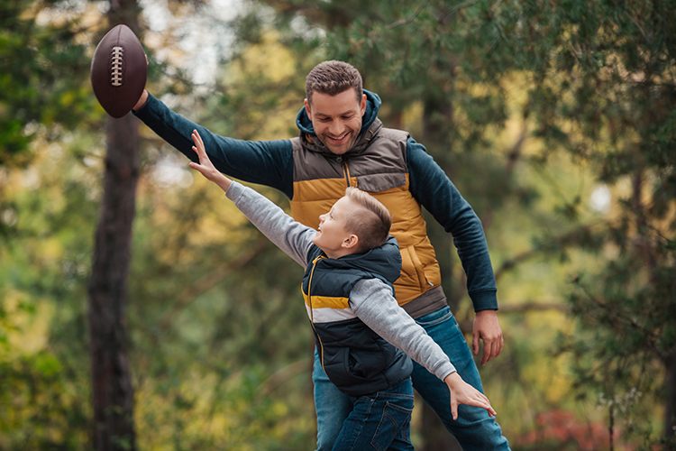 Father and Son Playing With a Ball in the Forest
